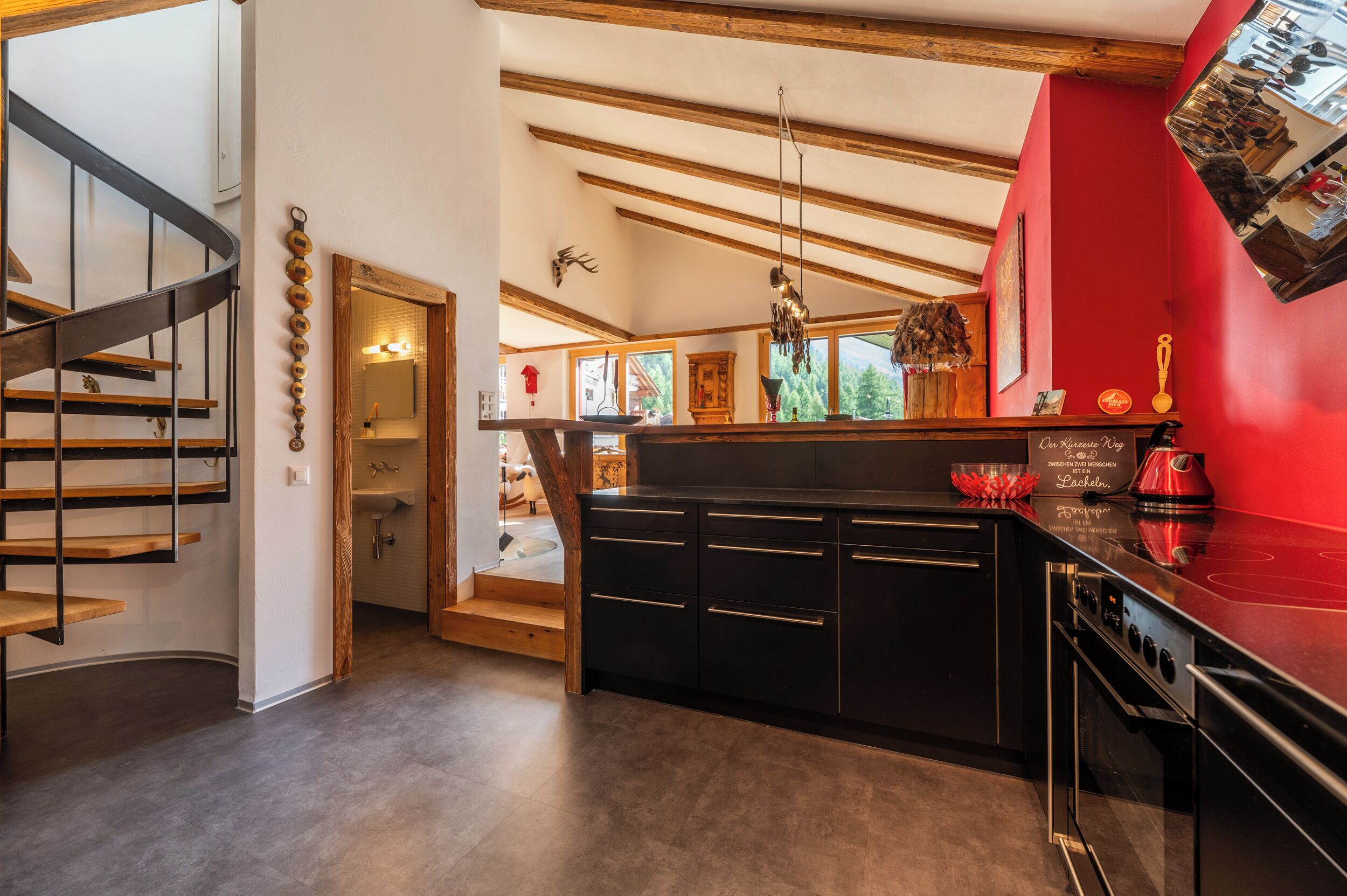A modern kitchen with a red accent wall, wooden beams, and a built-in stove.