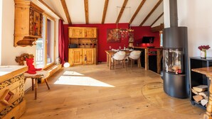 Una cocina acogedora con vigas de madera, una pared roja y una estufa moderna.