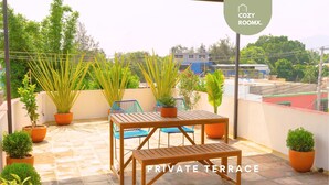 A private terrace with a wooden table and chairs, surrounded by potted plants and a view of the cityscape. - Style & Comfort  A/C Loft + Terrace + Pets (Oaxaca de Juárez)
