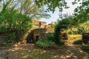 A stone structure with a doorway, surrounded by greenery and a building in the background. - Apartment 'Terrace Pool' with Wi-Fi (Vallabrix)