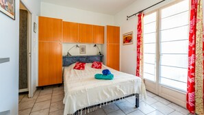 A bedroom with a bed, wooden cabinets, a window with curtains, and a tiled floor. - Apartment 'Villabrix Near Uzès' with Wi-Fi (Vallabrix)