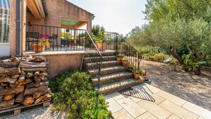 A house with a patio, outdoor seating, a staircase with railings, and a garden with various plants. - Apartment 'Villabrix Near Uzès' with Wi-Fi (Vallabrix)