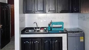 A kitchen with dark cabinets, a countertop, a sink, and a stove. - APARTAMENTO 1105T (Cartagena)