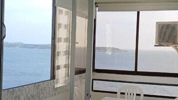 A balcony with a table and chairs, a sliding glass door, and a view of the sea. - APARTAMENTO 1105T (Cartagena)