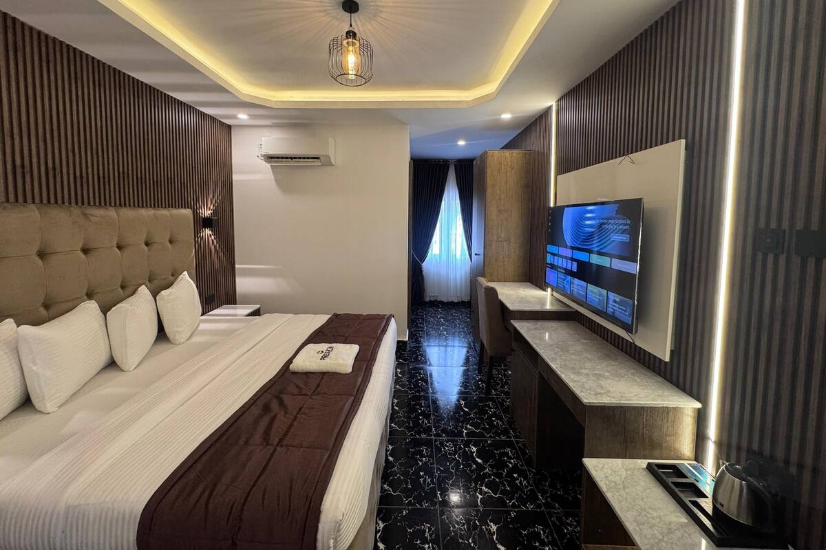 Una habitación de hotel moderna con una cama grande, un televisor de pantalla plana y suelo de mármol.
