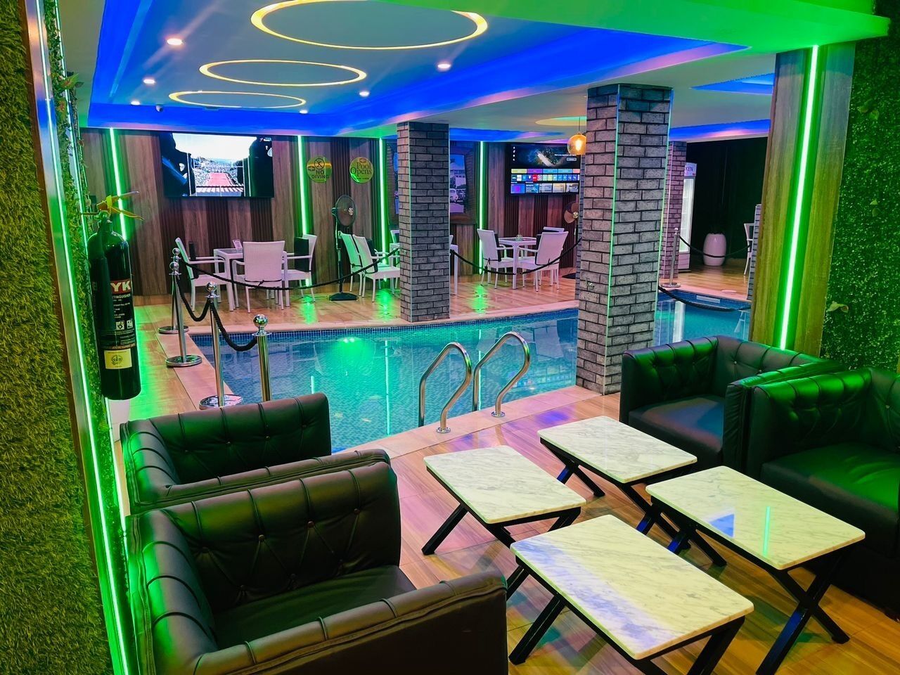 A modern indoor pool area with lounge seating and a bar.