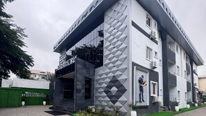 Un edificio moderno con fachada geométrica, una entrada acogedora y un jardín ajardinado.