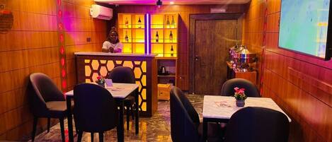 A restaurant with wooden paneling, a bar area, and a screen displaying a sports event.