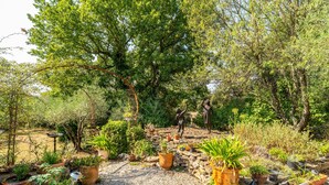 A garden with various potted plants, a stone pathway, and a sculpture of a person. - Holiday Home 'Obofix' with Wi-Fi (Vallabrix)