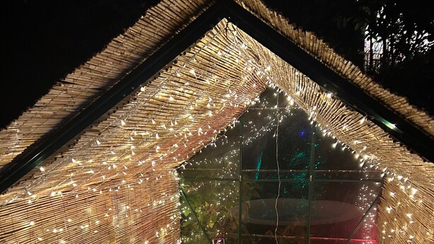 Un jacuzzi dentro de una estructura parecida a una carpa, con luces colgantes.