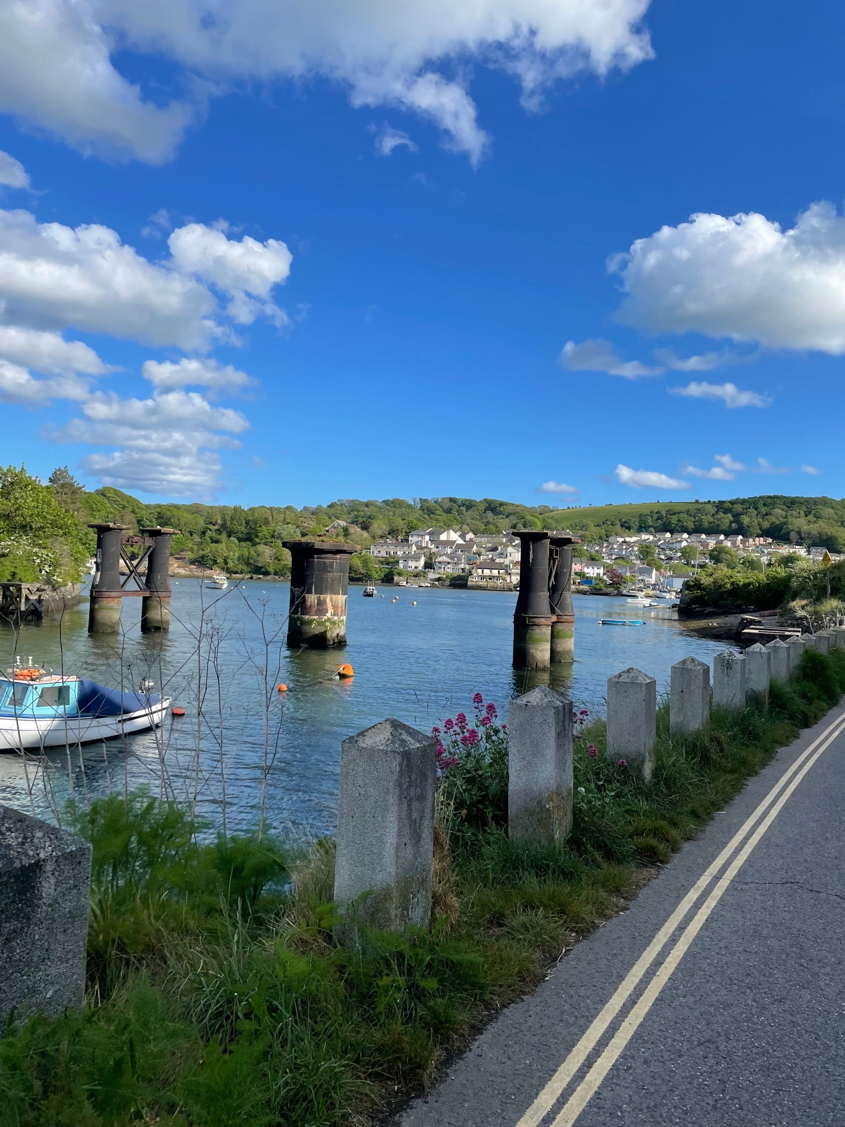 A river with a bridge, boats, and a road alongside.
