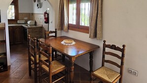 A dining area with a wooden table and chairs, a window with curtains, and an air conditioning unit above the window.