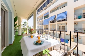 Ein Balkon mit Frühstückstisch, Blick ins Innere des Gebäudes und ein grüner Kunstturm.