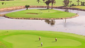 A golf course with a pond, palm trees, and a distant residential area. - 'Apartamento Zen Dreams Almerimar' with sea views, Wi-Fi, and air conditioning (Almerimar)