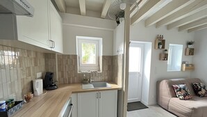 Une cuisine moderne avec une fenêtre, des meubles blancs, un évier et une machine à café.