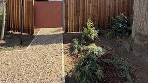 Une maison avec un toit en tuiles, une clôture en bois et une allée gravillonnée.
