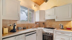 Una cocina con armarios blancos, lavavajillas, horno, ventana y lavadora.