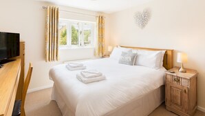 Ein Hotelzimmer mit Bett, Fernseher, Schreibtisch und einem Fenster mit Vorhängen.