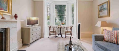 A living room with a fireplace, a television, a dining table with chairs, and a sofa.