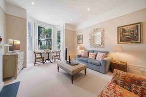 A living room with a sofa, a coffee table, a TV, and a dining area with chairs and a table.