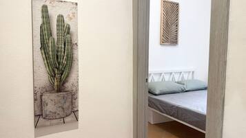 Une chambre à coucher comprenant un lit, une œuvre d’art représentant un cactus accrochée au mur, et un panneau décoratif en bois.