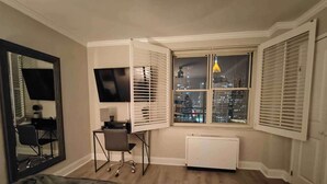 Une chambre avec vue sur la ville, un bureau avec une chaise, un lit et un radiateur.