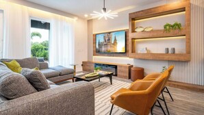 A modern living room with a sofa, coffee table, and a TV mounted on the wall. - Spacious 6-bedroom house in Reunion - Fully themed game room - xbox and more (Kissimmee)