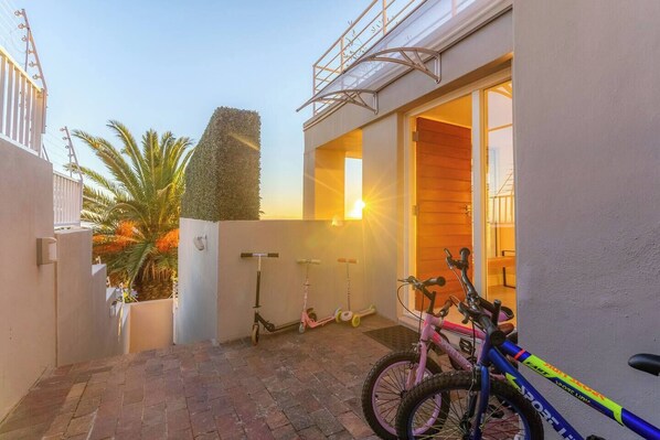Un quartier résidentiel avec une terrasse dallée, un vélo et une trottinette.