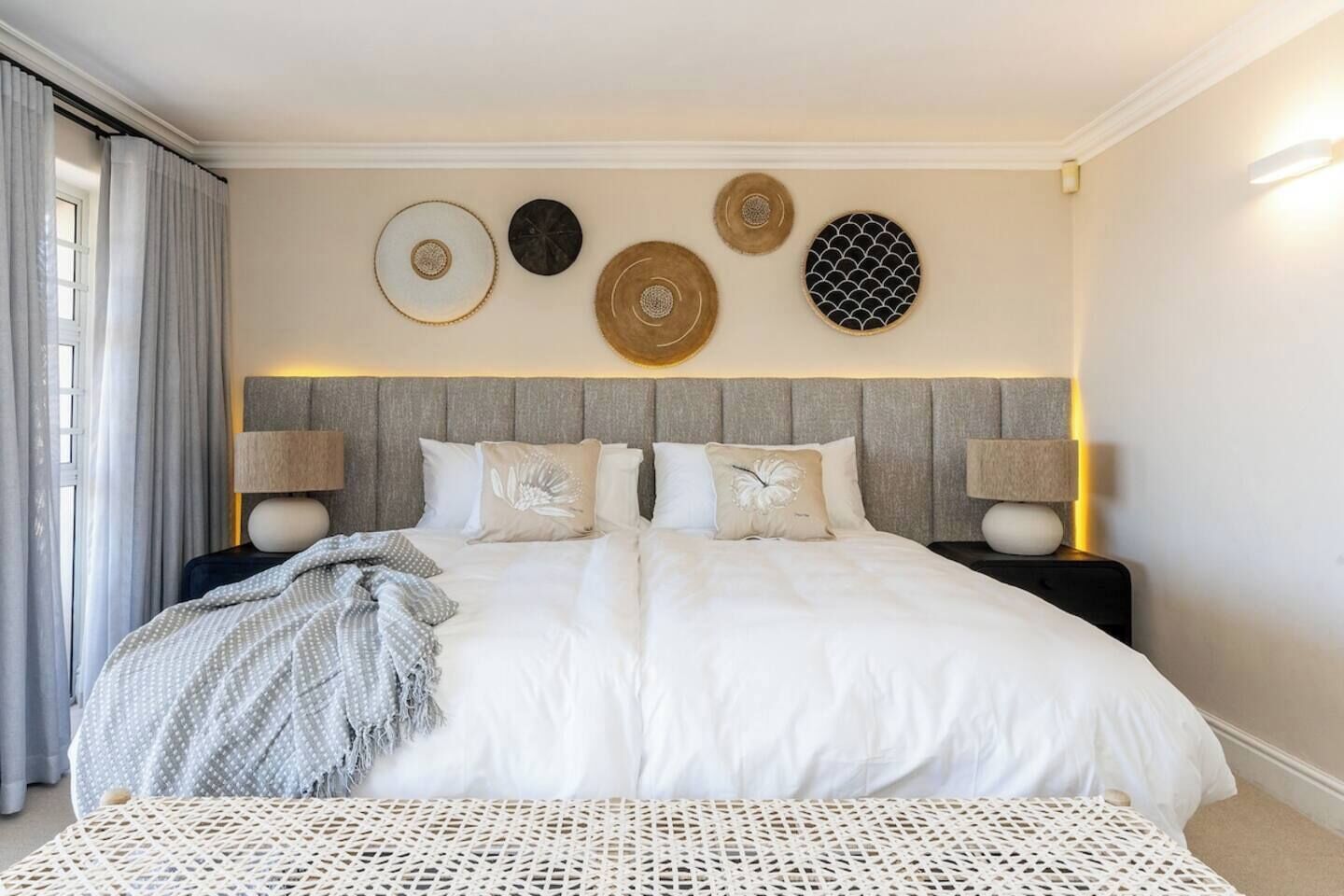 A hotel room with a large bed, two bedside tables, and a wall with decorative plates.