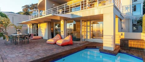 A modern house with a swimming pool, outdoor seating, and a balcony.
