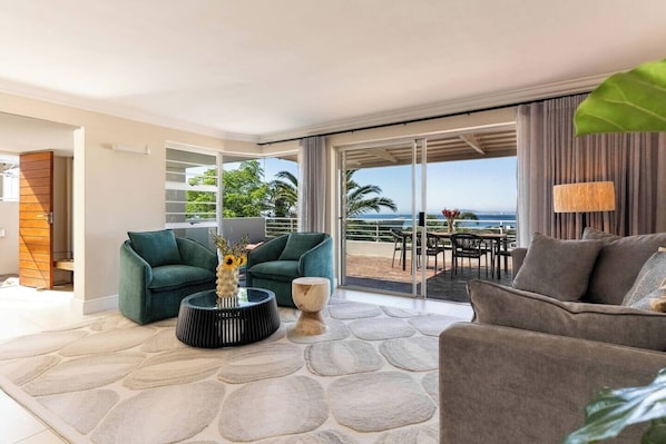A modern living room with a sofa, a coffee table, and a view of the outdoors.