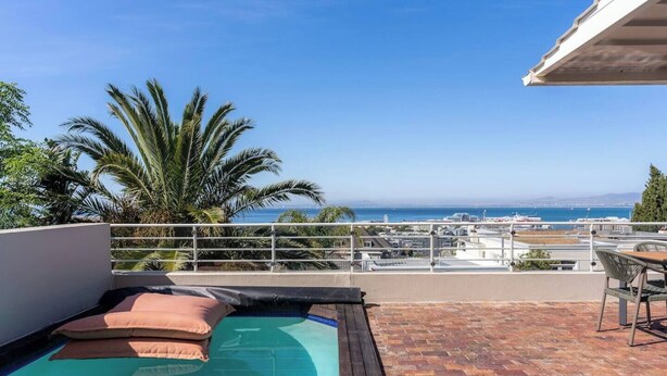 A rooftop pool with a view of the ocean and cityscape.