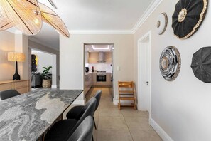 A dining area with a marble table, chairs, a lamp, and decorative wall art. - Your CT experience starts here (Cape Town)