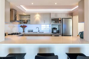 A modern kitchen with a central island, stainless steel appliances, and a built-in oven.