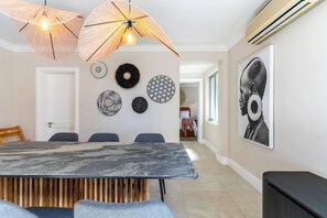 A dining area with a marble table, blue chairs, and a wooden slatted bench.