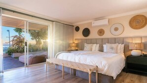A modern bedroom with a large bed, a bench, and a view of the outdoors. - Your CT experience starts here (Cape Town)