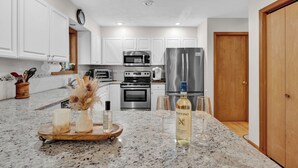 A modern kitchen with white cabinets, stainless steel appliances, and a granite countertop.