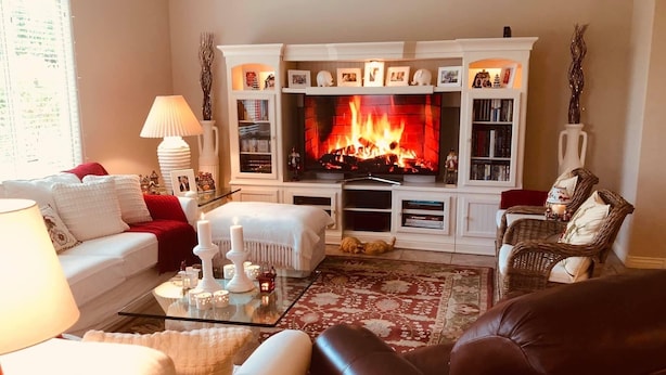 Ein gemütliches Wohnzimmer mit Kamin, weißen Möbeln und einem roten Teppich.