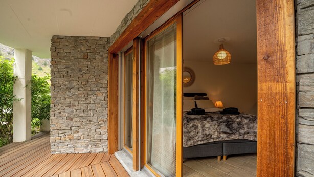 Un dormitorio con pared de piedra, suelo de madera y una cama con un plaid de piel.