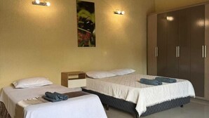 Une chambre d’hôtel avec deux lits, une armoire et des lampes fixées au mur.