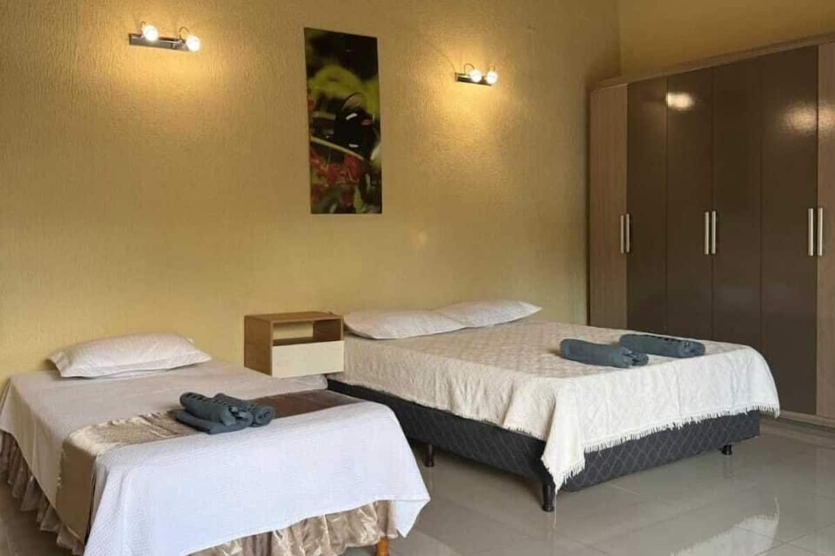 Une chambre d’hôtel avec deux lits, une armoire et des lampes fixées au mur.