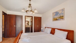 Ein Hotelzimmer mit einem großen Bett, einem Holzkopfende, einer Kristallleuchtre, einem Gemälde an der Wand und einem Spiegel im Hintergrund.