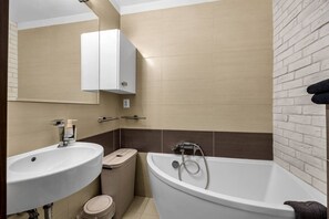 Une salle de bain moderne avec un lavabo blanc, une baignoire et un miroir au-dessus du lavabo.