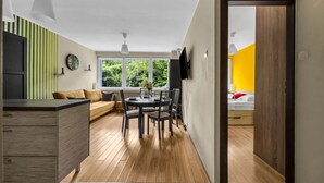 A modern kitchen with a dining area, a sofa, and a bed in the adjacent room.