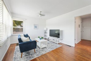 A modern living room with a blue sofa, white coffee table, and a flat-screen TV. - Private 3 Units| 5 Beds | Close to Beach & Bars (San Diego)