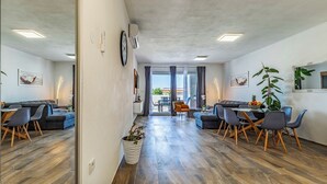 A modern living room with a sofa, dining table, chairs, and a potted plant. - Istriensonne 0785 - Newly built semi-detached house Double1 with private pool (Loborika)
