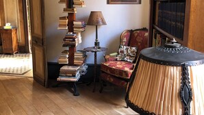 Una habitación con una estantería de madera, una lámpara, una silla y un cuadro en el suelo.