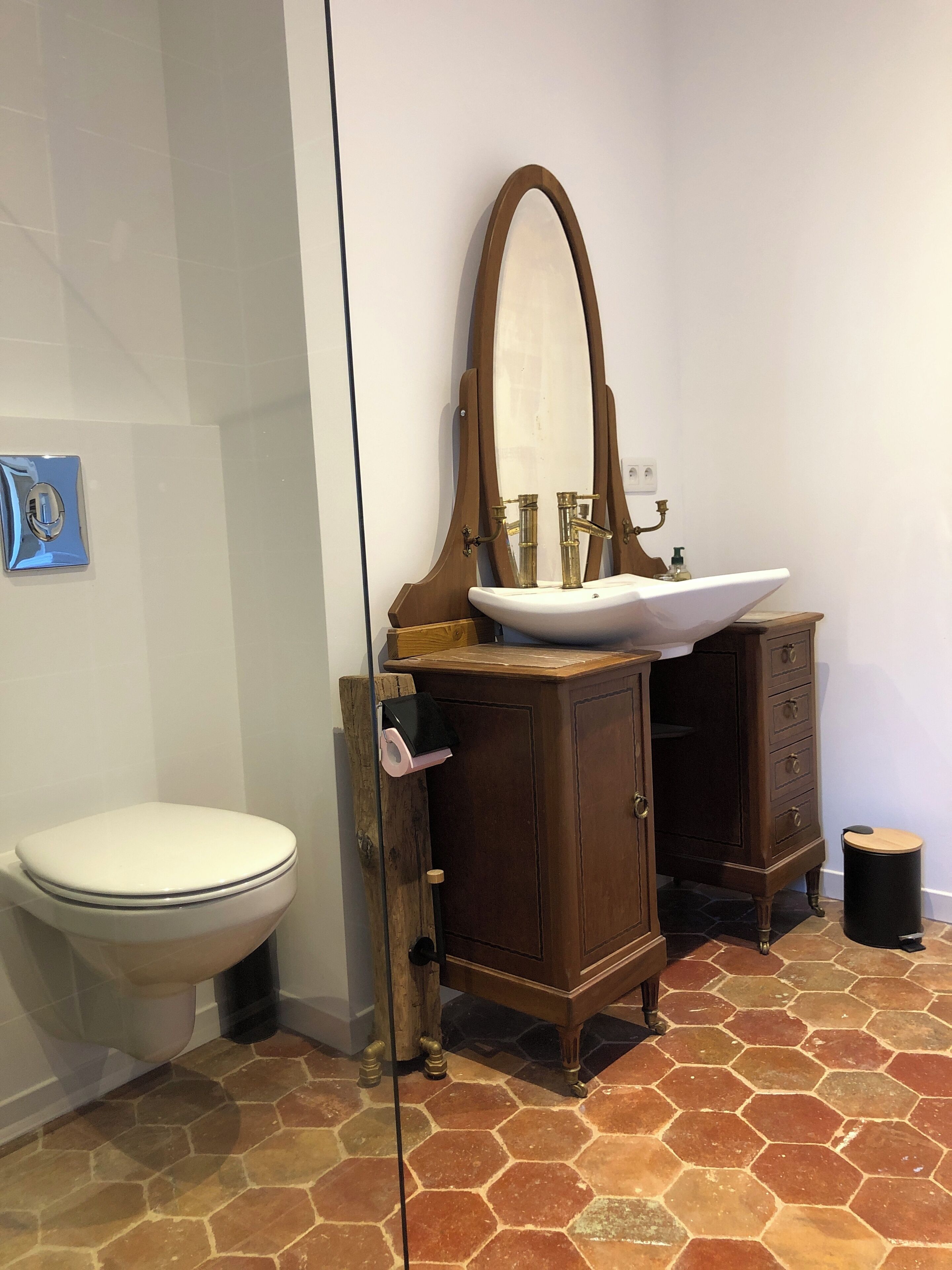 Un baño con inodoro, lavabo con espejo y un armario.