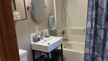 A full bathroom with a toilet, sink, mirror, and bathtub.