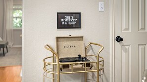 A room with a wall-mounted shelf holding a record player, a framed sign, and a framed nameplate. - 
Travis Heights Modern Getaway - Corporate Housing Rental (Austin)